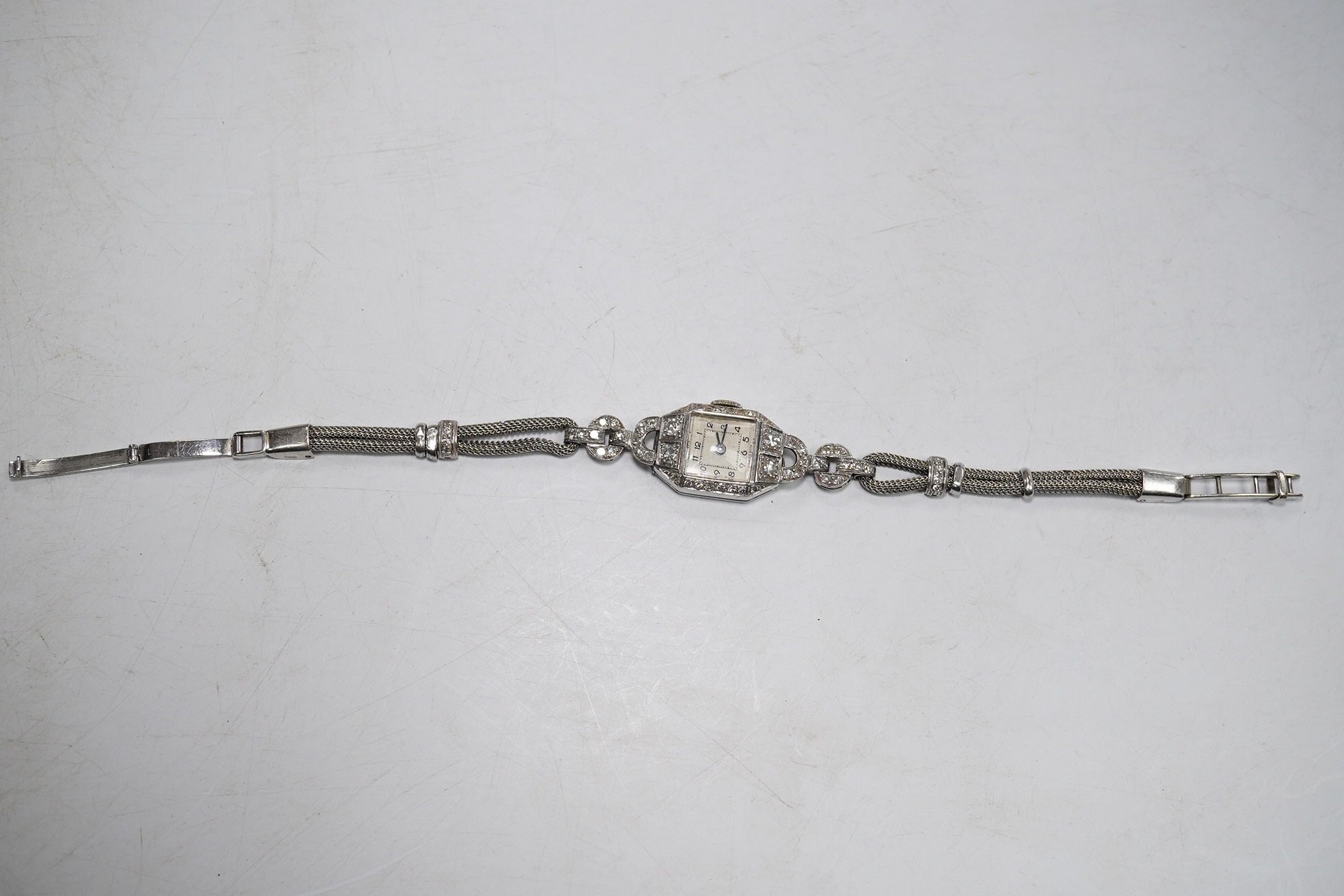 A lady's 1950's white metal and diamond cluster set manual wind cocktail watch, on a 9ct white gold bracelet, overall length 17.5cm, gross weight 17.1 grams. Condition - fair